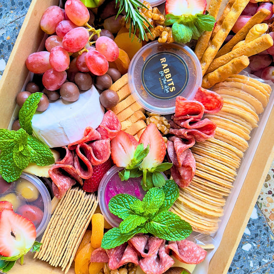 A gourmet cheese platter with a variety of cheeses, meats, fruits, and crackers, arranged neatly for serving.